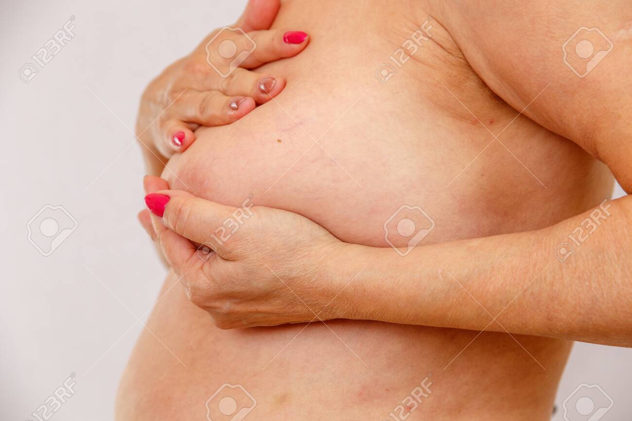 60 Year Old Older Woman Checks Her Big Breasts For Cancer On A Light Isolated Stock Photo Picture and Royalty Free Image. Image 128295978.