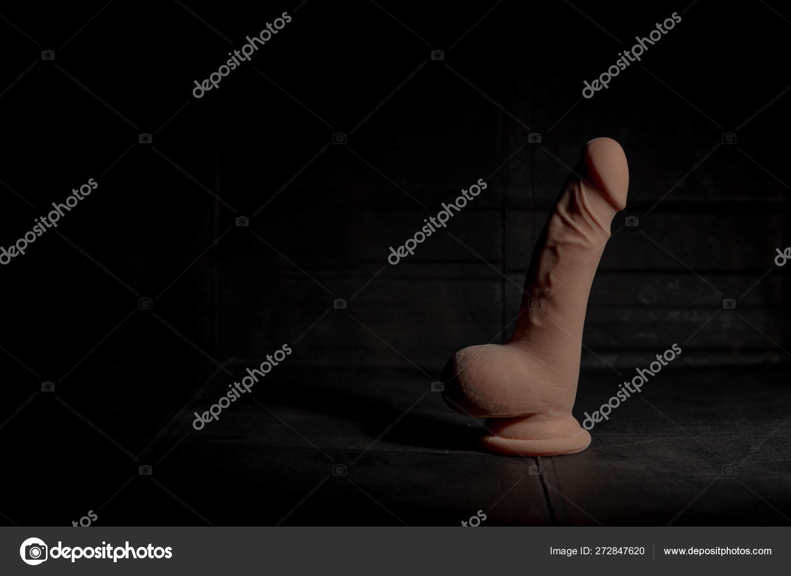 Very realistic dildo with balls on dirty dark background with hard light and shadow Stock Photo booblikuk 272847620