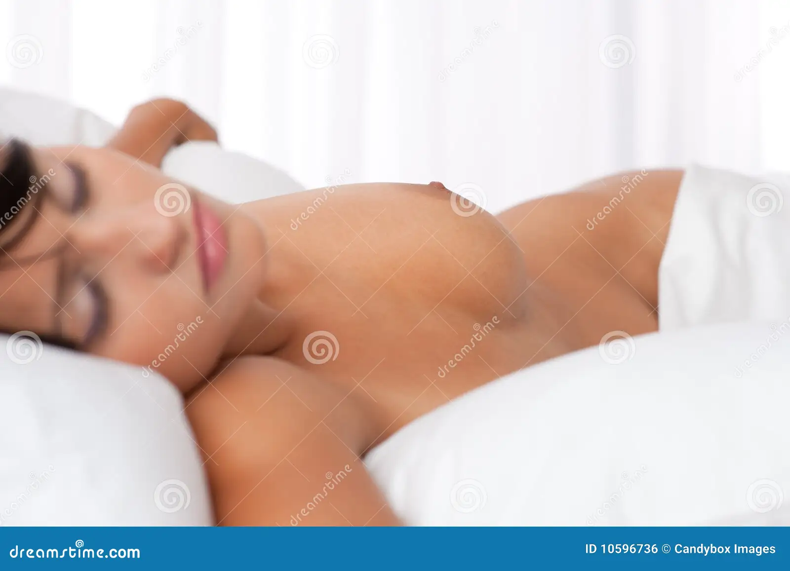 Young Woman Sleeping Naked in White Bed Stock Photo